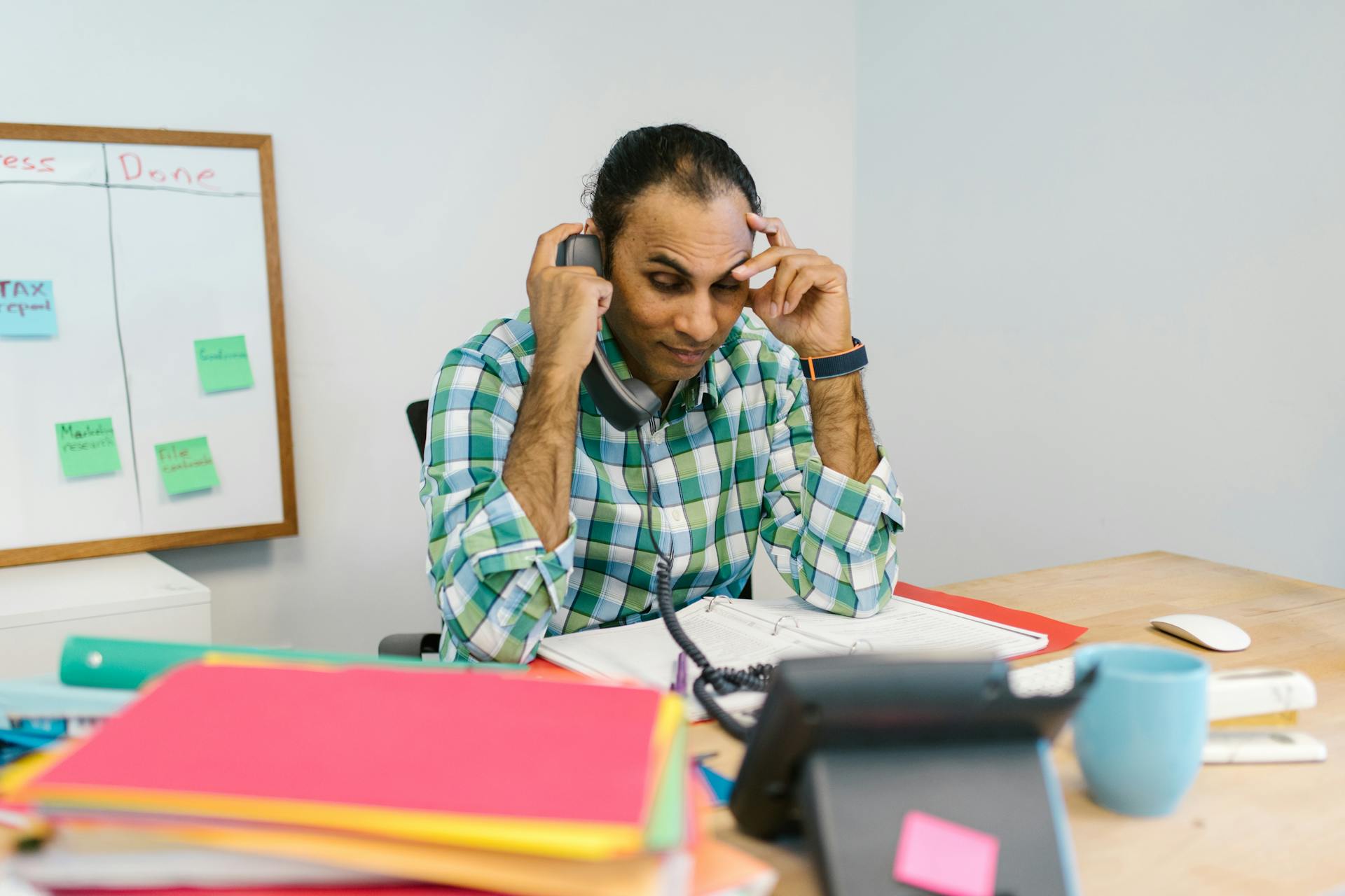 Stressed businessman talking on phone surrounded by paperwork
