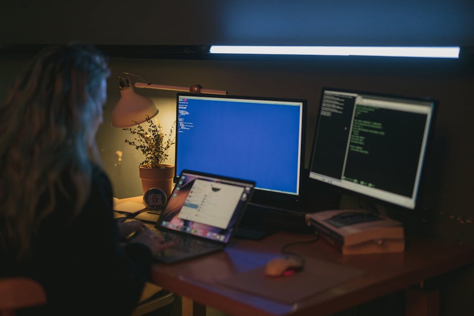 Woman working across multiple computer screens managing different software systems