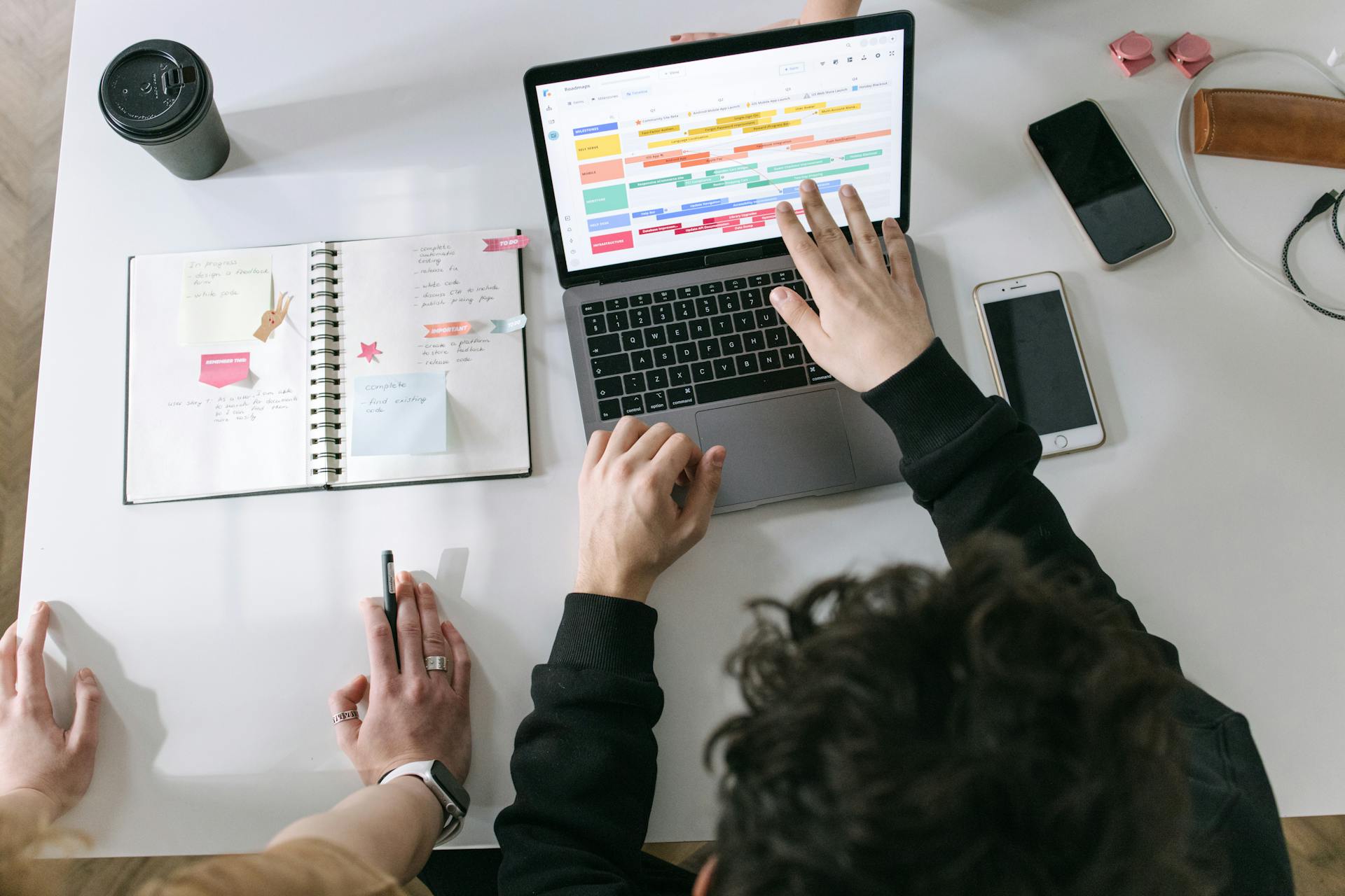 Person using MacBook Pro with calendar and smartphone for scheduling