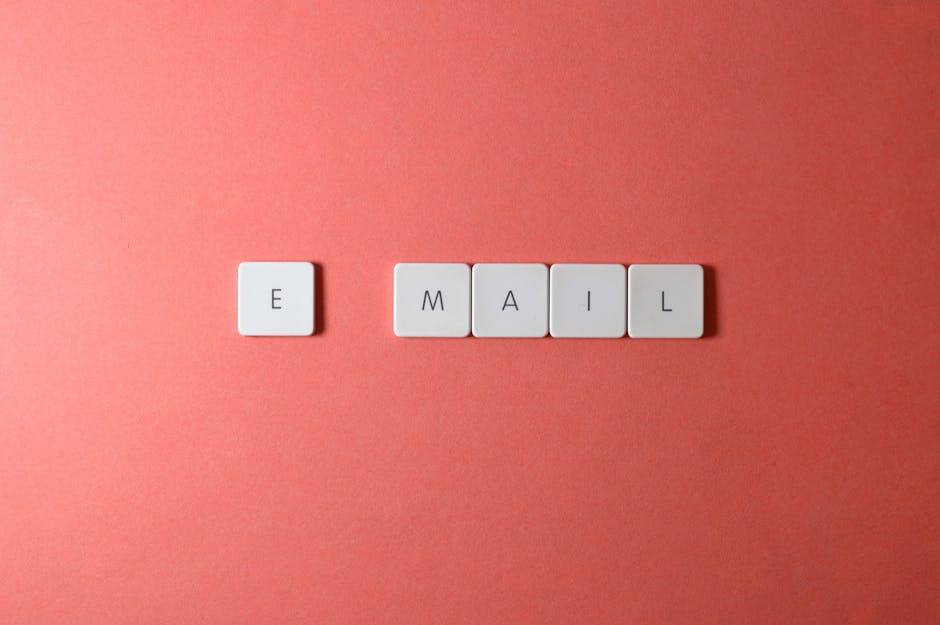 Flat lay of keyboard letter tiles spelling email on coral backdrop