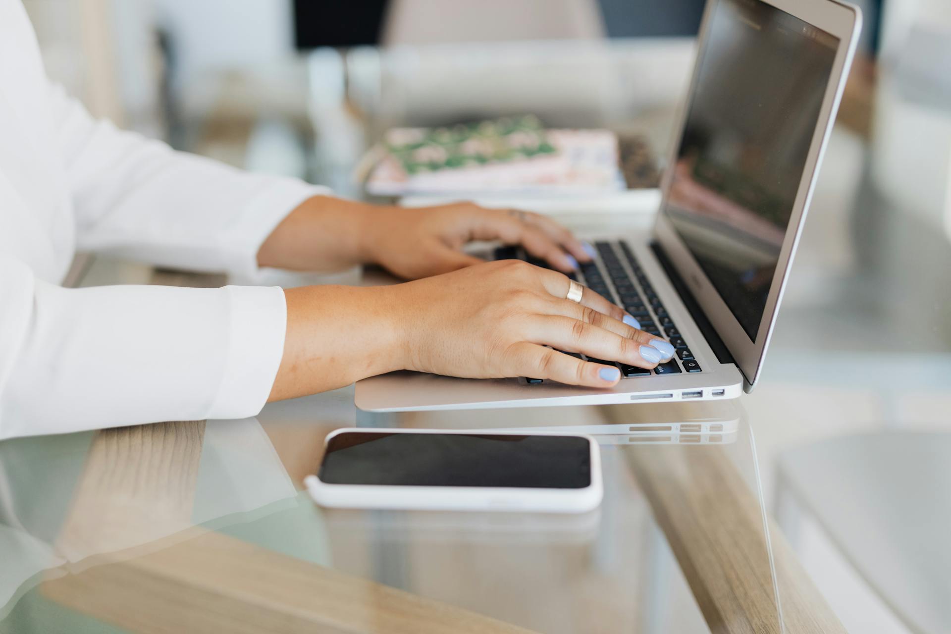 Professional using smartphone and laptop at modern workspace