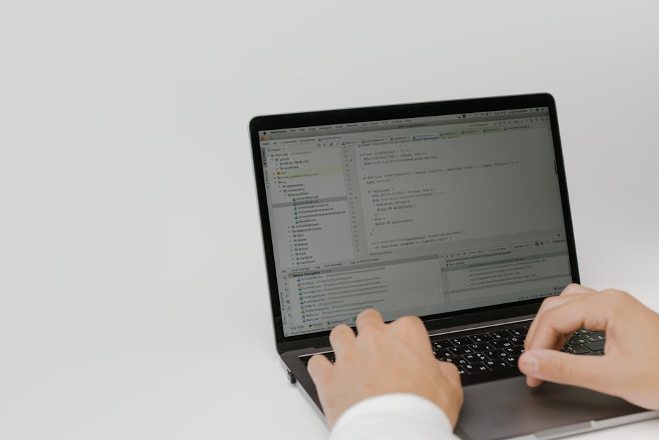 Person working on a laptop with software tools open, representing the complexity of managing multiple SaaS platforms